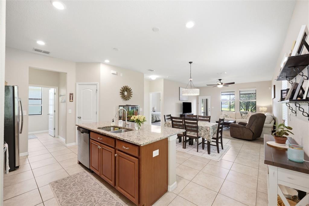 A kitchen island with granite countertops overlooks an open-concept dining area and living room — 11767 LAKE BOULEVARD, NEW PORT RICHEY, FL