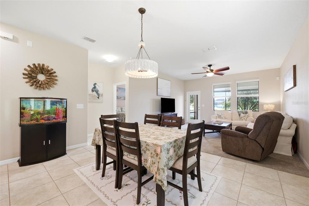 An open-concept dining and living area features tile flooring, a chandelier, and a fish tank — 11767 LAKE BOULEVARD, NEW PORT RICHEY, FL