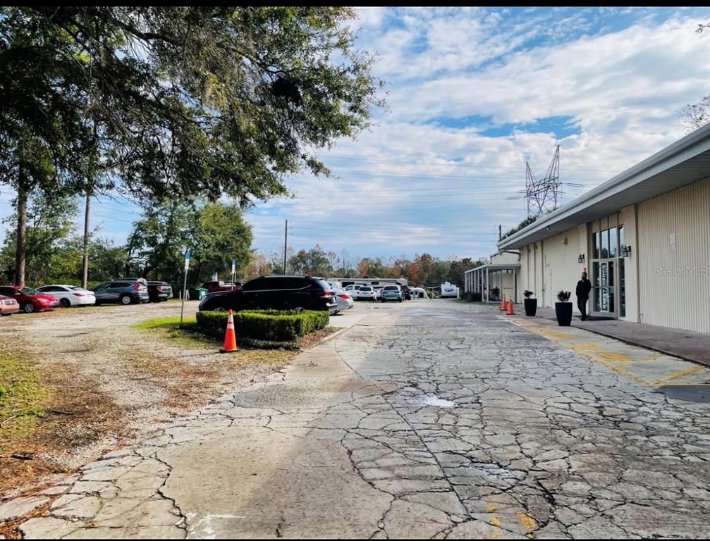 A gravel parking lot sits beside a commercial building with a cracked concrete entrance — 7540 GRAND AVE, WINTER PARK, FL