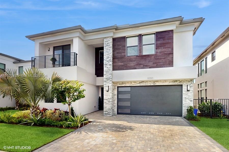 A two-story modern house features a stone-accented facade, a dark garage door, and a balcony — 8350 Royal County Down Rd, Boca Raton FL 33434, BOCA RATON, FL