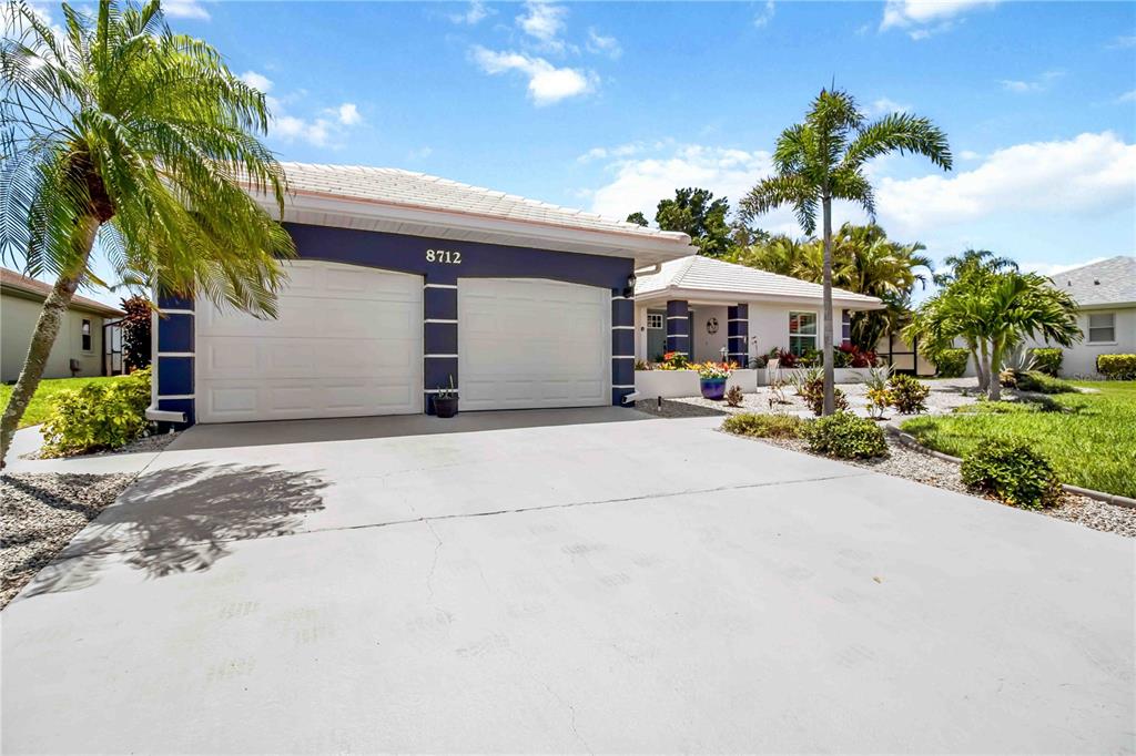 A single-story house with a two-car garage, a blue facade, and palm trees — 8712 53RD AVENUE W, BRADENTON, FL