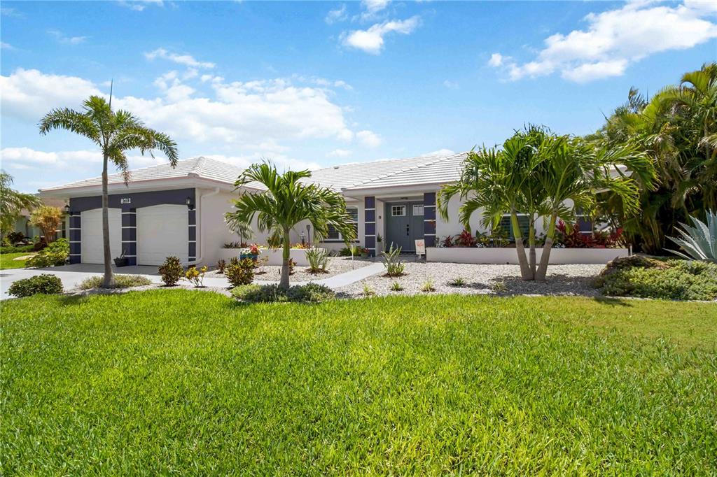 A single-story house with a white tile roof, a two-car garage, and palm trees — 8712 53RD AVENUE W, BRADENTON, FL