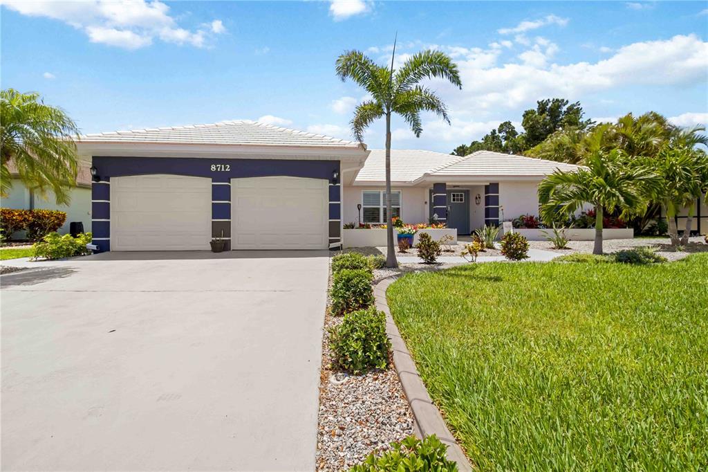 A single-story house with a two-car garage, a palm tree, and a landscaped front yard — 8712 53RD AVENUE W, BRADENTON, FL