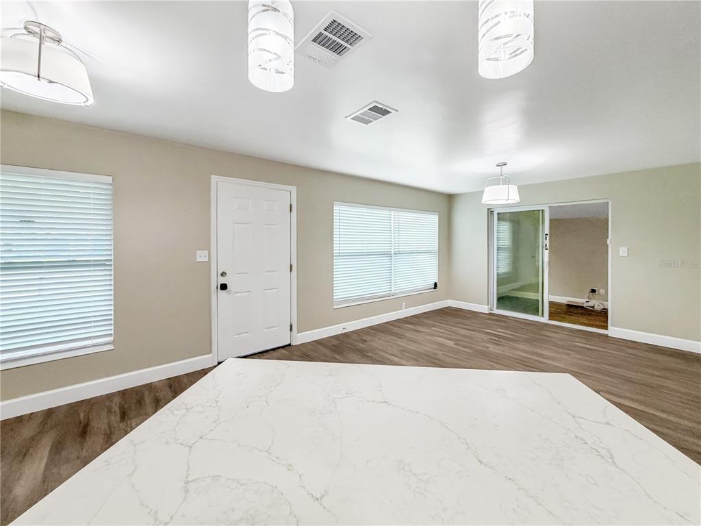 A bright room features a white quartz island, wood-look flooring, and a sliding glass door — 4228 KIRKLAND BOULEVARD, ORLANDO, FL