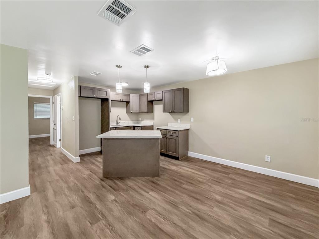 A kitchen features dark wood cabinets, a central island, and light-colored flooring — 4228 KIRKLAND BOULEVARD, ORLANDO, FL