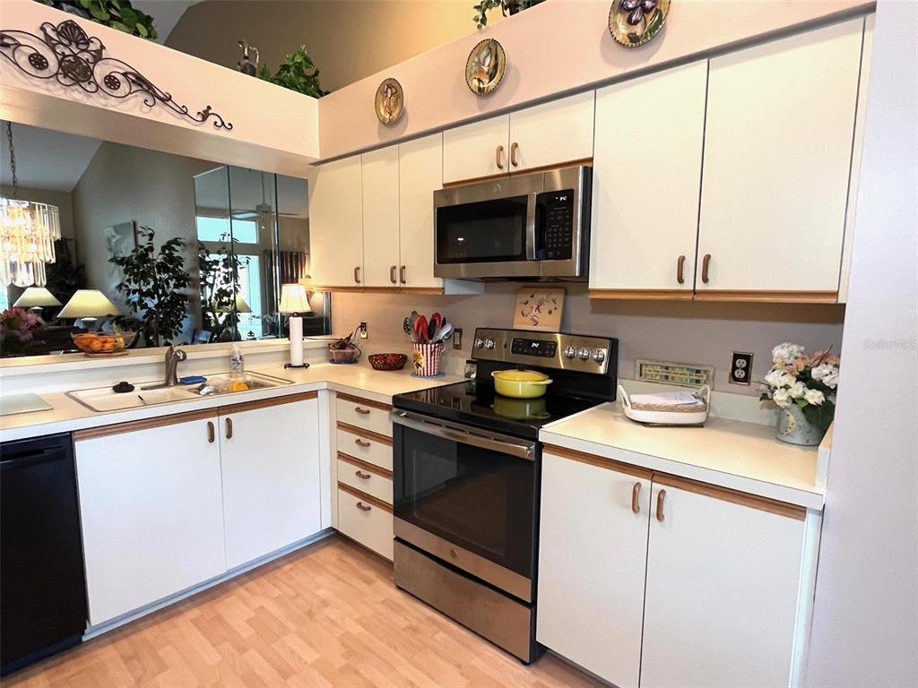 A kitchen features white cabinets, stainless steel appliances, and light-colored countertops — 6713 STONE RIVER RD UNIT 203, BRADENTON, FL