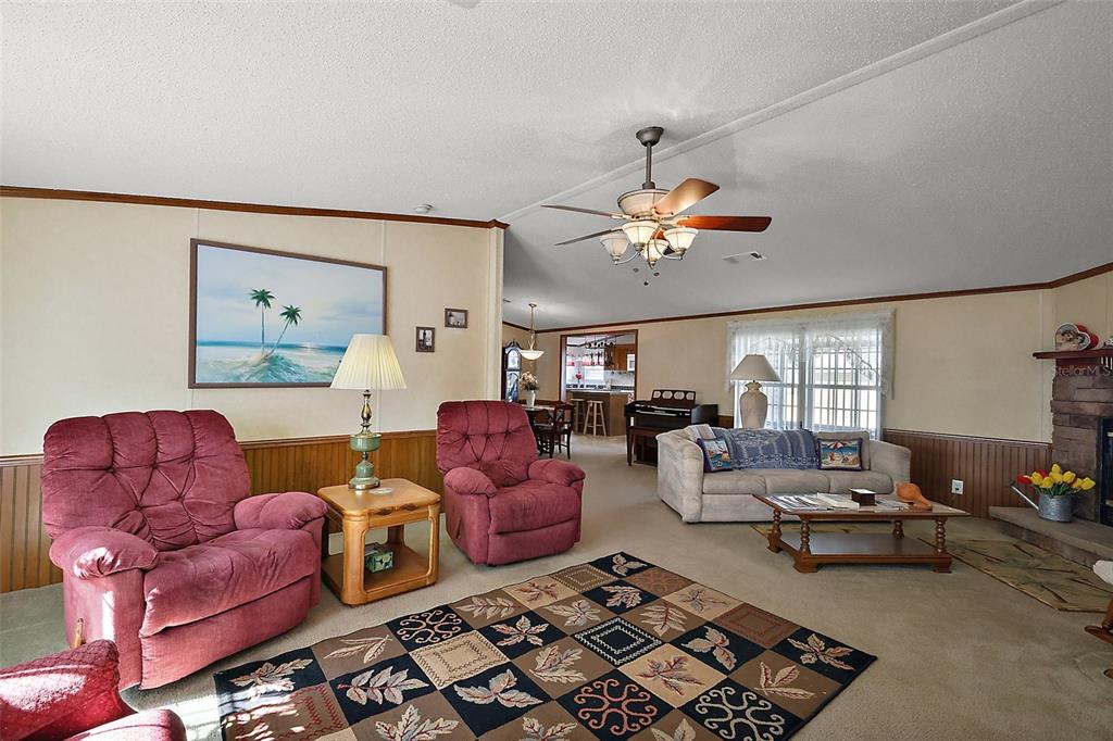 A living room features two red recliners, a beige sofa, and a patterned area rug — 37945 MONTICELLO STREET, LEESBURG, FL