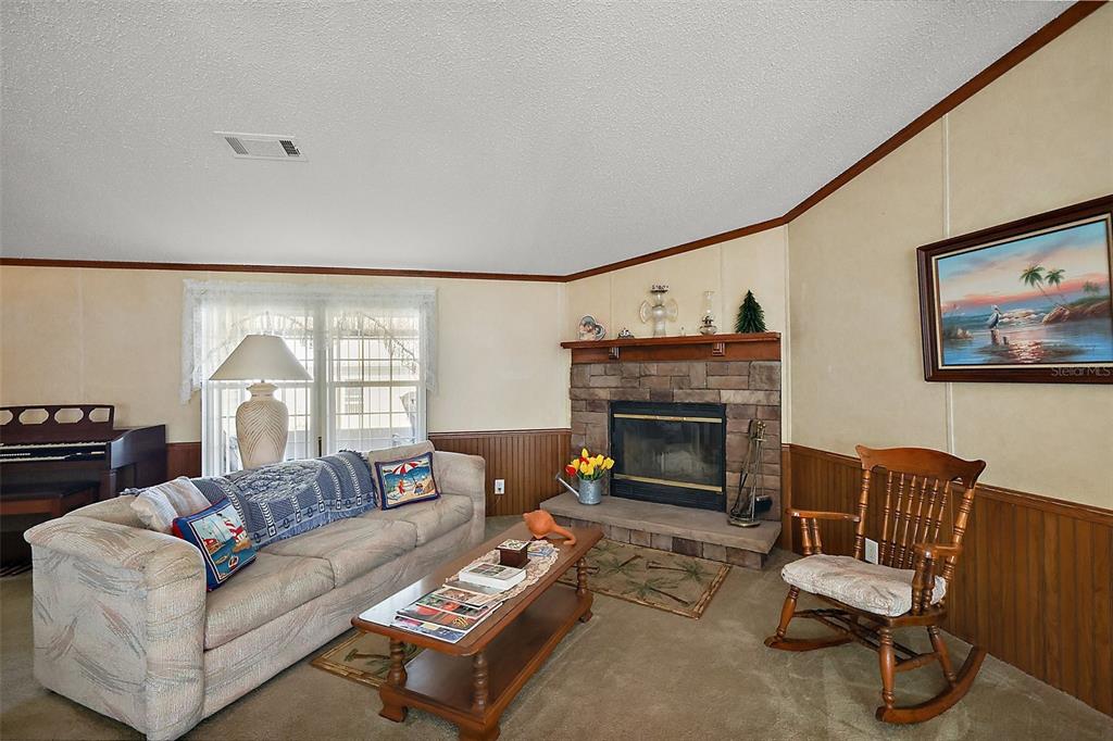 A living room features a stone fireplace, a beige sofa, and a wooden rocking chair — 37945 MONTICELLO STREET, LEESBURG, FL