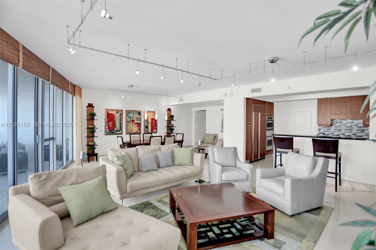 A spacious living and dining area features neutral furniture, track lighting, and a modern kitchen — 3101 S Ocean Dr, Hollywood FL 33019, HOLLYWOOD, FL