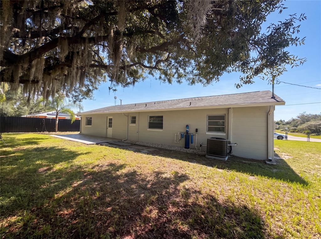 The exterior of a single-story house features a concrete patio and a water filtration system — 417 CALUMET ROAD, AVON PARK, FL