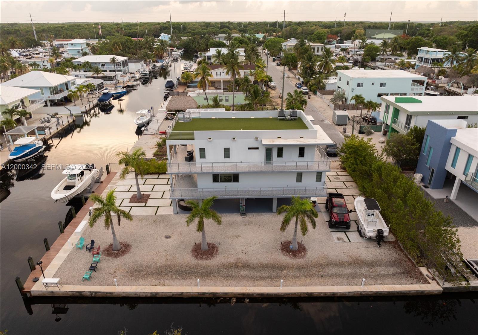 An aerial view shows a modern white multi-story house with a green roof beside a canal — 475 Bahia Honda Rd, Key Largo FL 33037, KEY LARGO, FL