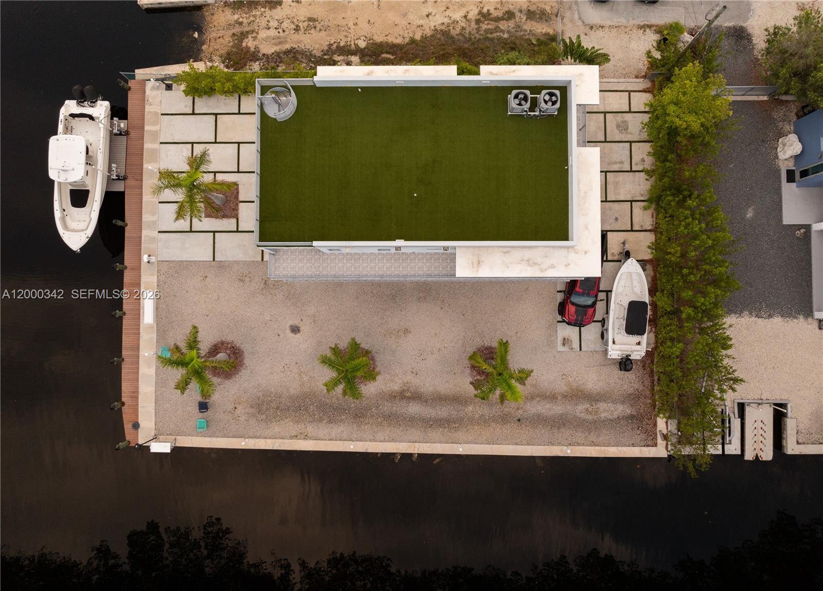 An aerial view shows a house with a rooftop lawn, palm trees, and two boats — 475 Bahia Honda Rd, Key Largo FL 33037, KEY LARGO, FL