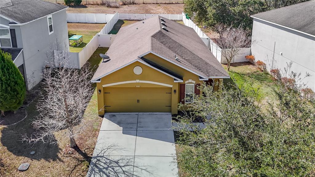 An aerial view shows a yellow single-story house with a two-car garage and driveway — 13221 WATERFORD CASTLE DRIVE, DADE CITY, FL