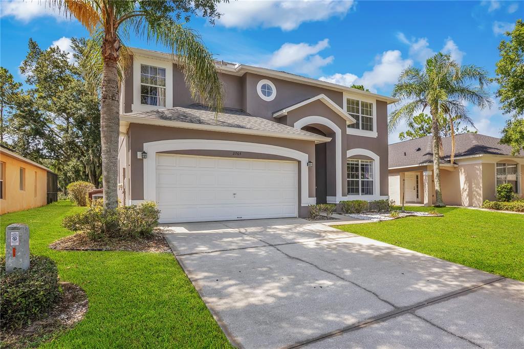 A two-story house with a two-car garage, gray stucco exterior, and palm trees in front — 2765 KOKOMO LOOP, HAINES CITY, FL