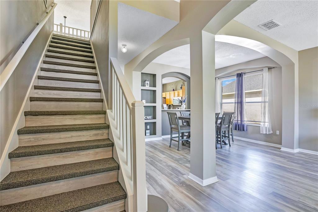 A staircase with carpeted treads leads to an upper level near an open dining area — 2765 KOKOMO LOOP, HAINES CITY, FL