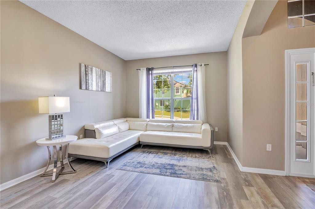 A living room features a white sectional sofa, a side table with a lamp, and flooring — 2765 KOKOMO LOOP, HAINES CITY, FL