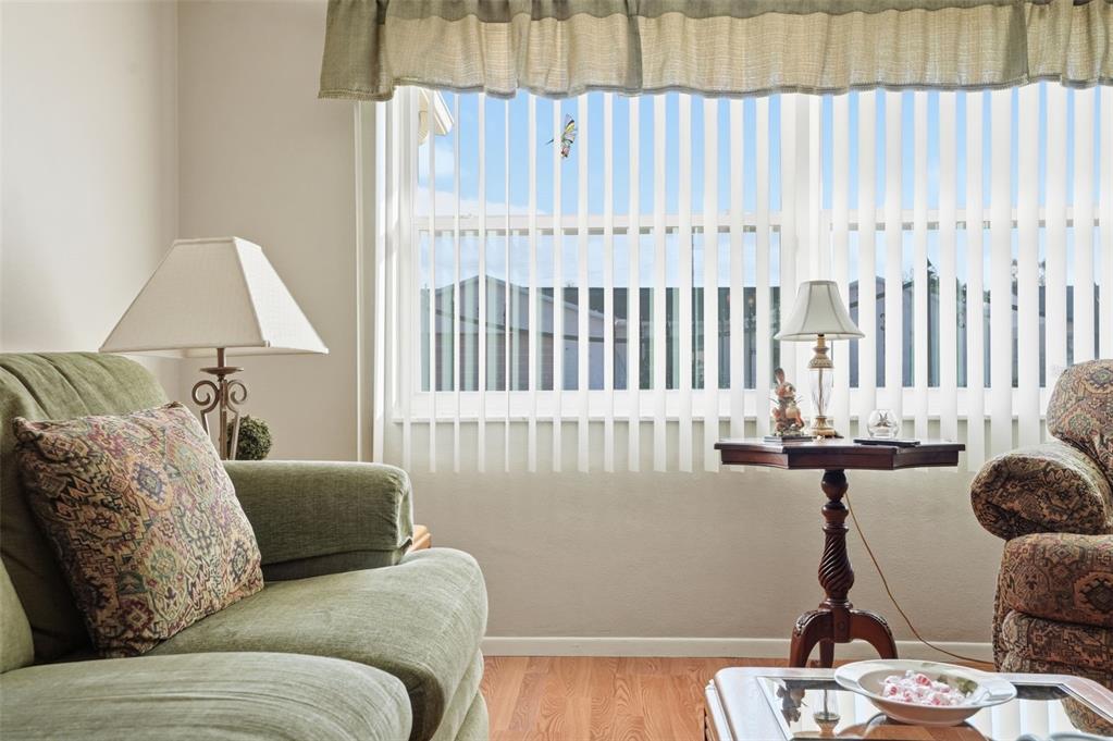 A living room features a green sofa, a small side table with a lamp, and windows — 7329 CAY DRIVE, PORT RICHEY, FL