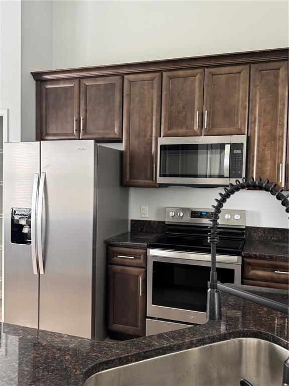 A kitchen features dark wood cabinets, stainless steel appliances, and dark granite countertops — 1767 CAMBRIDGE VILLAGE COURT, OCOEE, FL
