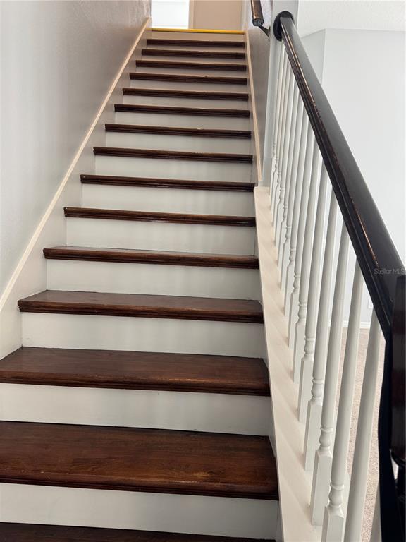A wooden staircase with white risers and a dark handrail leads to an upper level — 1767 CAMBRIDGE VILLAGE COURT, OCOEE, FL