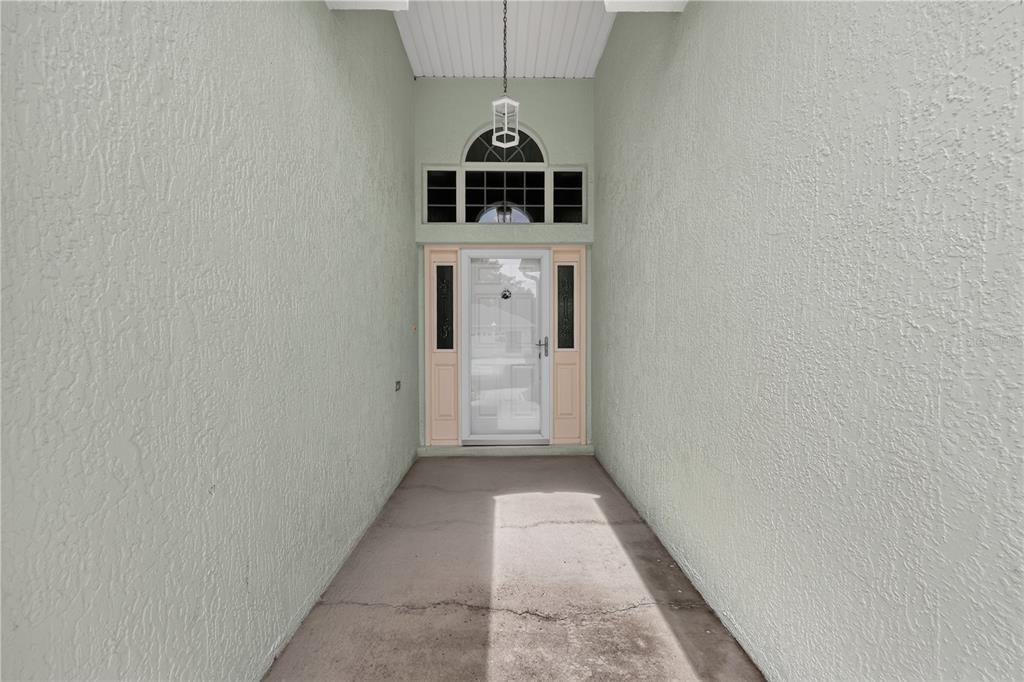 A covered entryway features a white front door with sidelights and a transom window — 11042 SW 73RD COURT, OCALA, FL