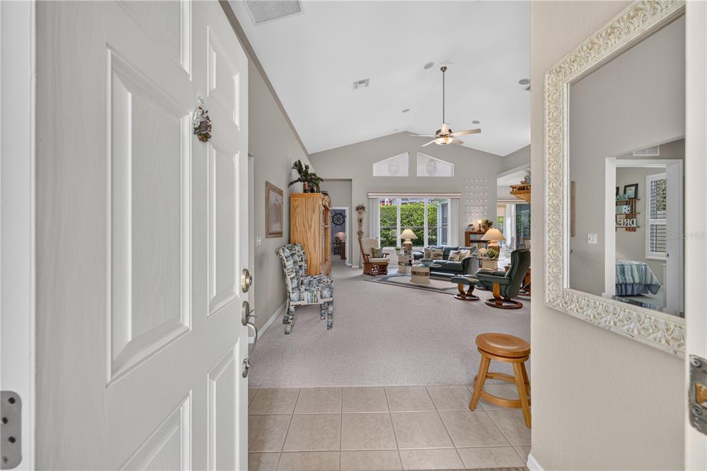 A view from an open front door into a living room with vaulted ceilings — 11042 SW 73RD COURT, OCALA, FL