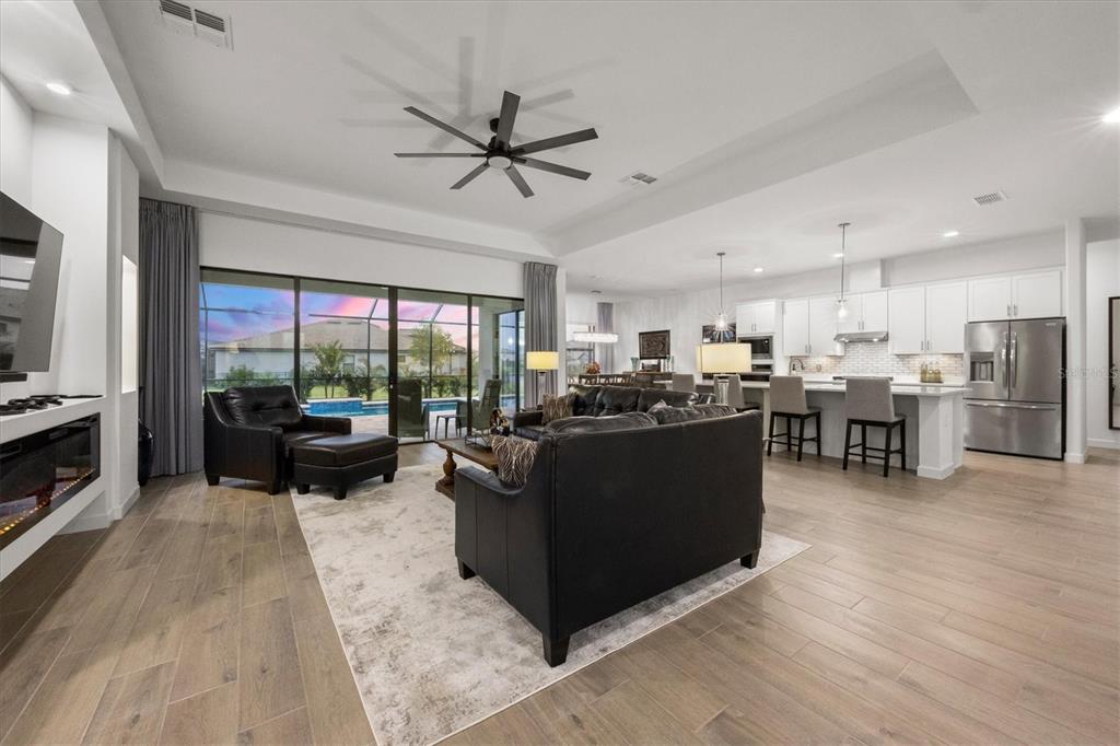 An open-concept living room and kitchen featuring wood-look tile flooring and a sliding glass door — 15306 GOLDEN BEAM PLACE, BRADENTON, FL