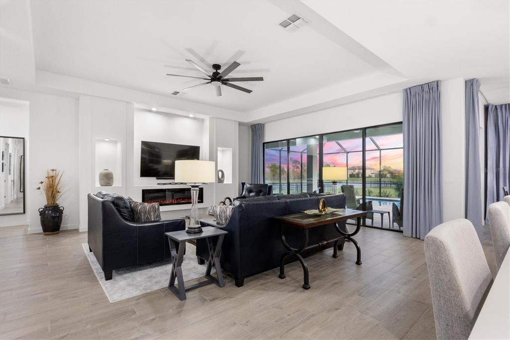A modern living room features dark leather sofas, a fireplace, and large sliding glass doors — 15306 GOLDEN BEAM PLACE, BRADENTON, FL