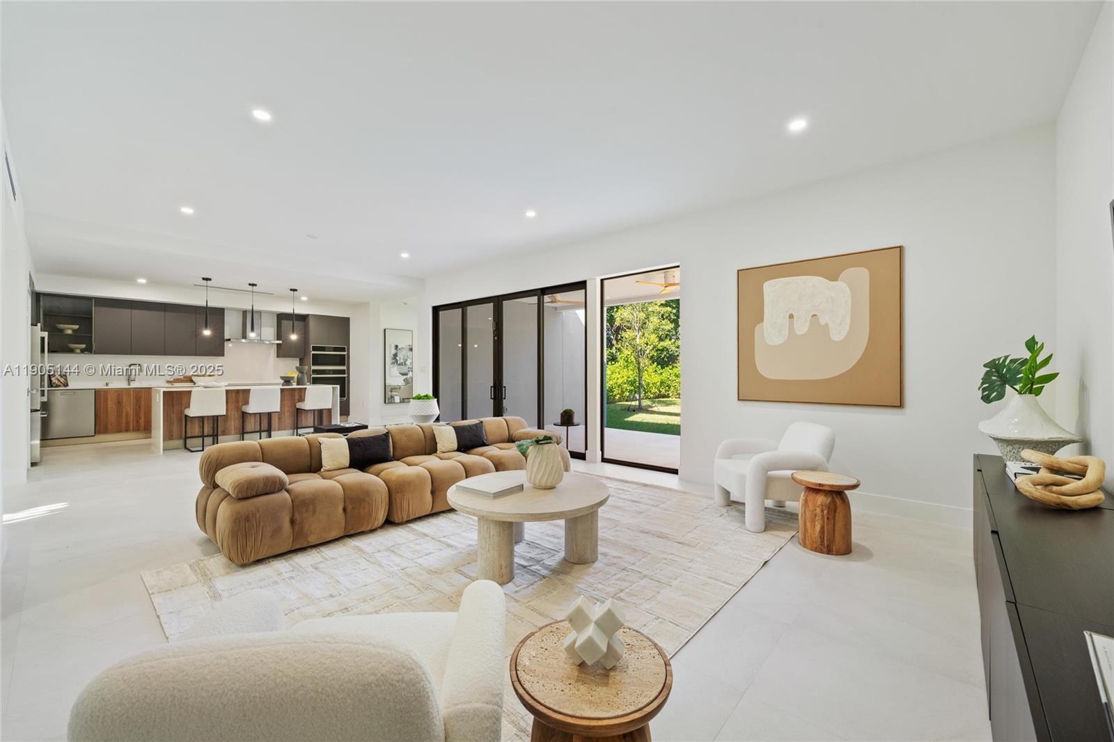 A modern open-concept living room features a brown sectional sofa, white armchairs, and a kitchen — 2127 SW 11th Ter, Miami FL 33135, MIAMI, FL