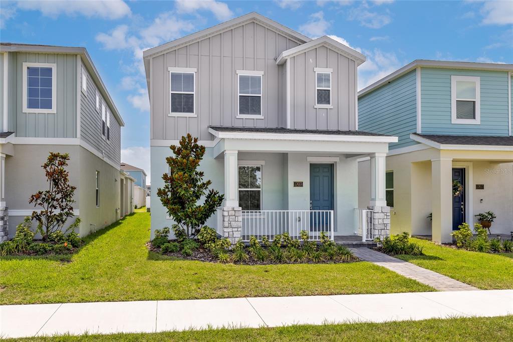 A two-story house with light gray vertical siding and a front porch with stone pillars — 13023 TRANQUIL WATER ALLEY, WINTER GARDEN, FL
