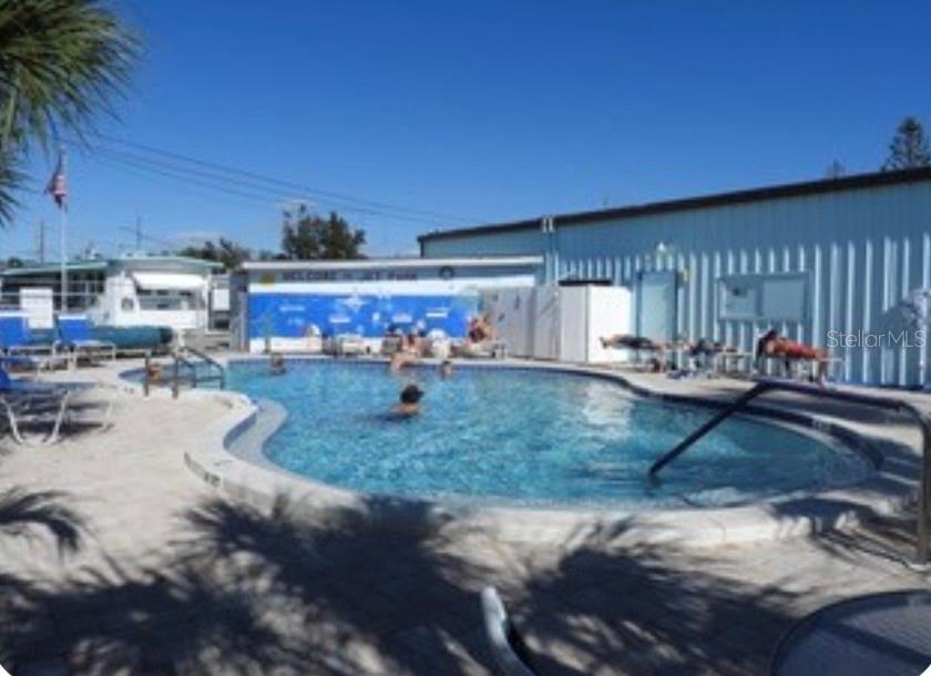 An outdoor swimming pool surrounded by a paved deck with lounge chairs and a building — 167 4TH STREET W, PALMETTO, FL