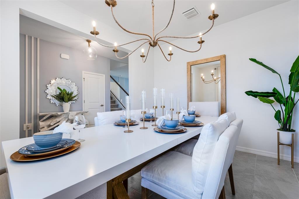 A bright dining room features a white table, upholstered chairs, a chandelier, and a mirror — 13560 TURNLEAF BOULEVARD, PUNTA GORDA, FL