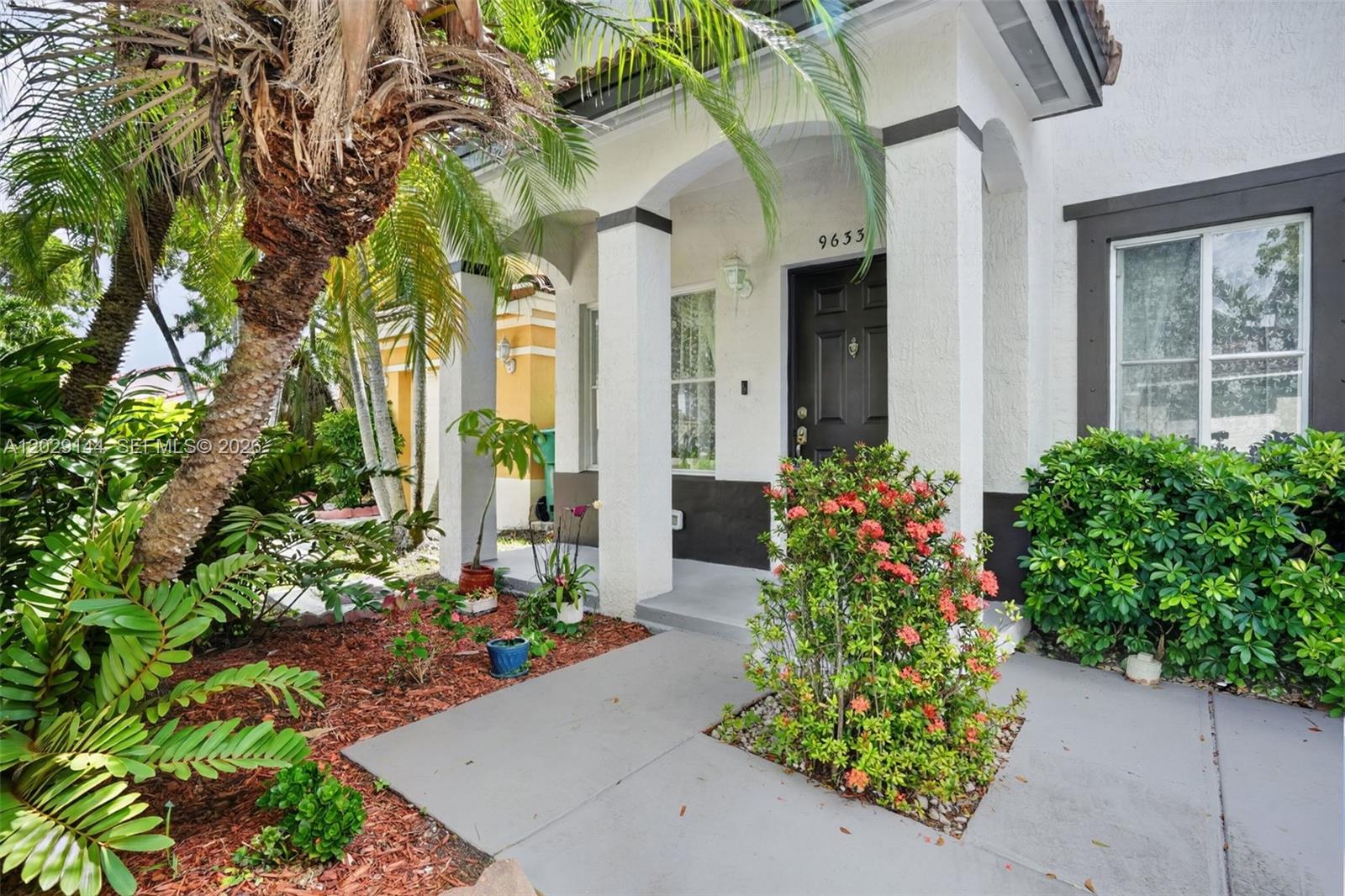 The exterior of a house features a covered entryway, a dark door, and landscaping — 9633 SW 163rd Ct, Miami FL 33196, MIAMI, FL