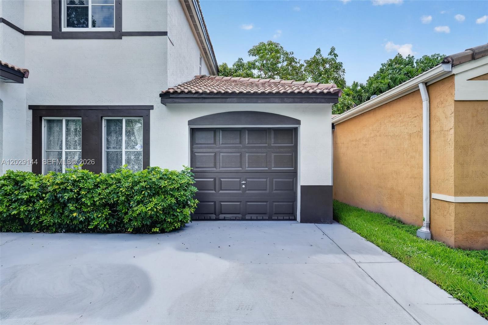 A single-car garage with a brown door is attached to a two-story stucco house — 9633 SW 163rd Ct, Miami FL 33196, MIAMI, FL