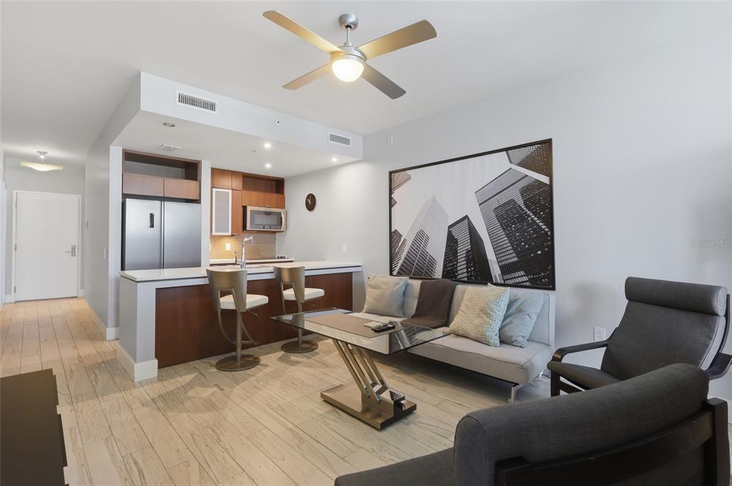 A modern living room and kitchen area with wood-look tile flooring and a ceiling fan — 111 N 12TH STREET UNIT 1310, TAMPA, FL