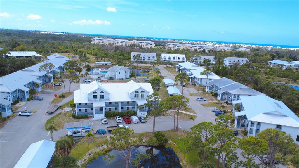 An aerial view shows multiple white multi-story residential buildings surrounded by trees and parking lots — 6800 PLACIDA ROAD UNIT 179, ENGLEWOOD, FL