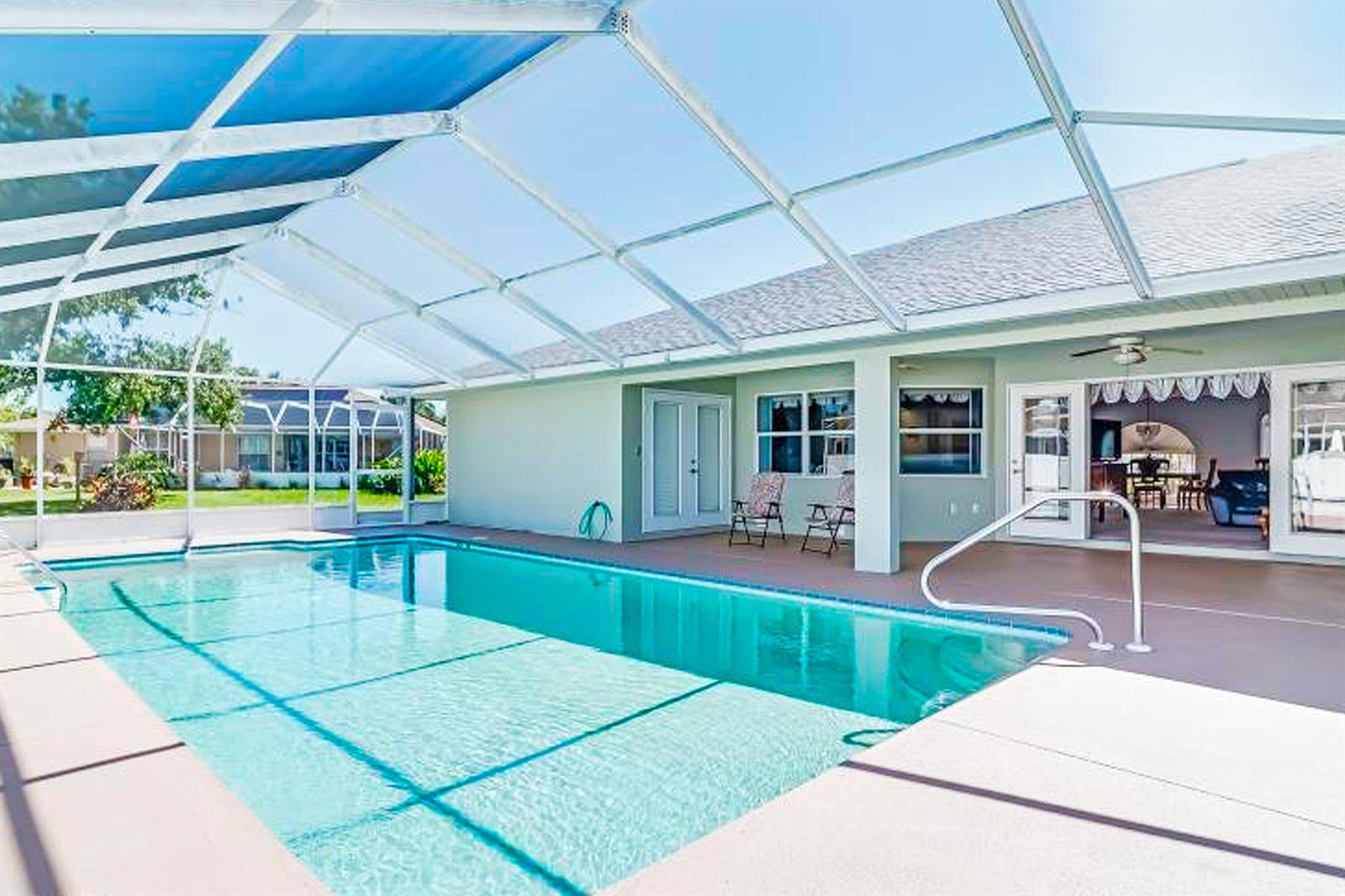 A swimming pool with a screen enclosure sits on a patio outside a house — 424 Holly Drive, Sebring FL 33876, SEBRING, FL
