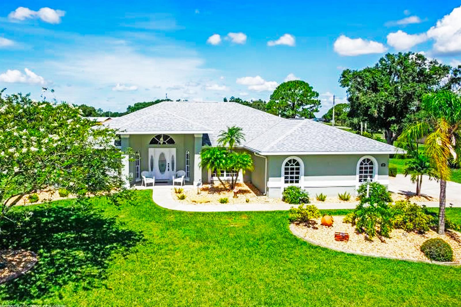 A single-story house with a light gray exterior, arched windows, and a landscaped front yard — 424 Holly Drive, Sebring FL 33876, SEBRING, FL
