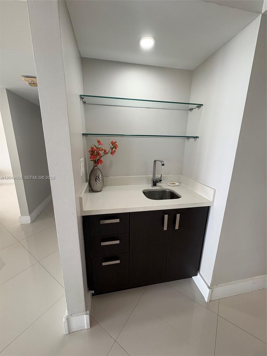 A wet bar features dark cabinetry, a white countertop, a sink, and two glass shelves — 1717 N Bayshore Dr # 2054, Miami FL 33132, MIAMI, FL