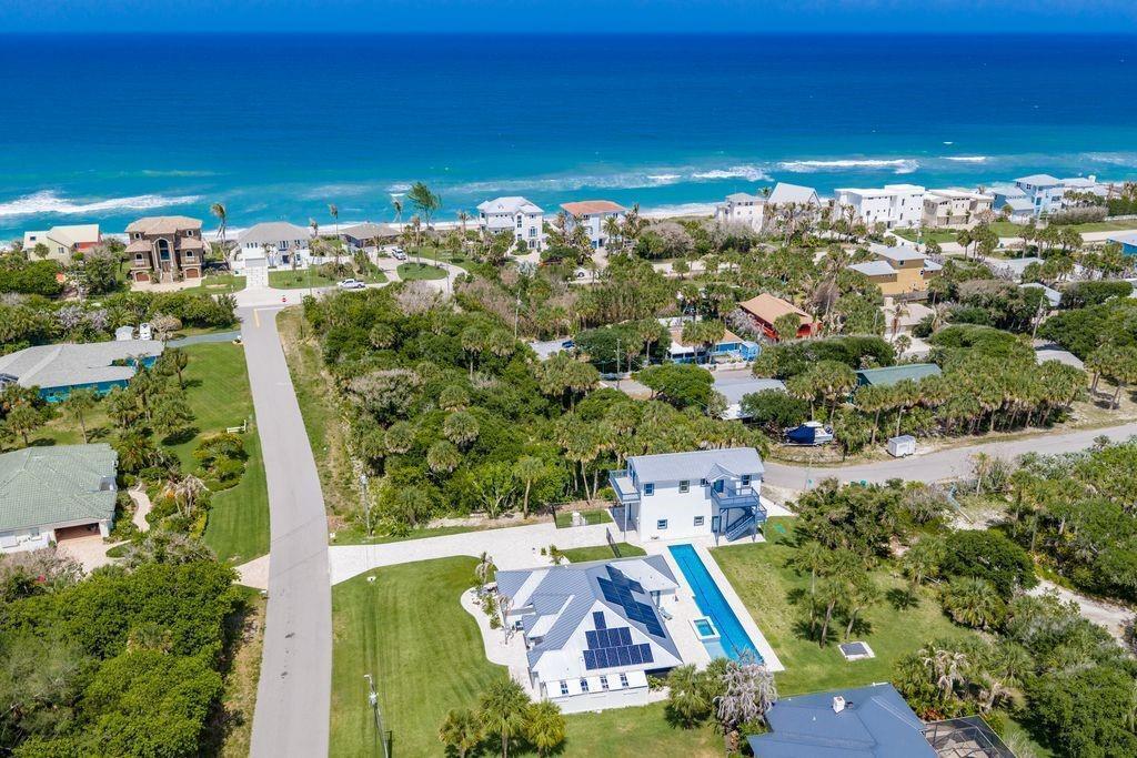 An aerial view shows a coastal neighborhood with houses, lush vegetation, and the ocean beyond — MELBOURNE BEACH, FL