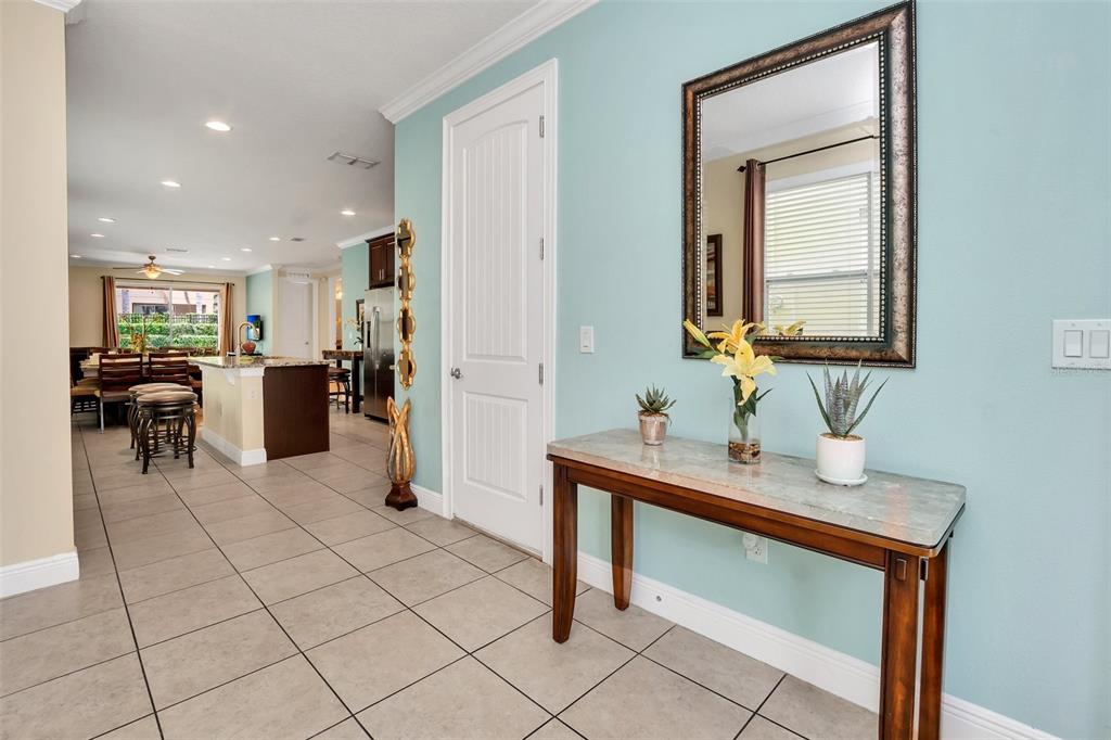 A tiled entryway features a console table with a mirror and a view into the kitchen — 450 NOVI PATH, KISSIMMEE, FL