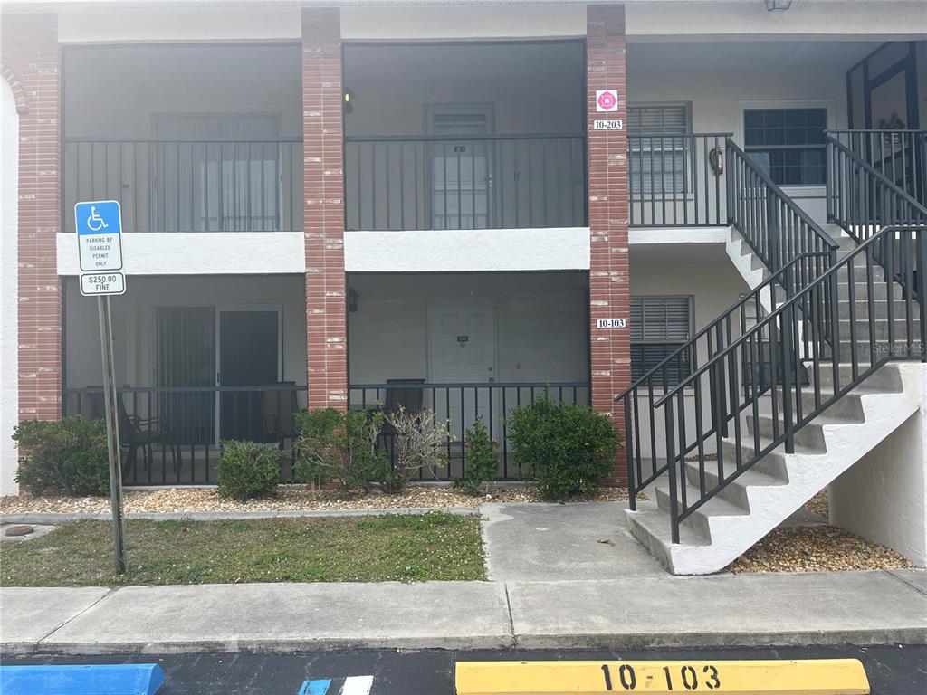A two-story apartment building exterior features a ground-level patio, upper balcony, and concrete stairs — 1531 PLACIDA ROAD UNIT 10-103, ENGLEWOOD, FL