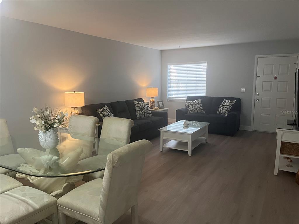 A living and dining area features light wood flooring, gray walls, and dark furniture — 1531 PLACIDA ROAD UNIT 10-103, ENGLEWOOD, FL