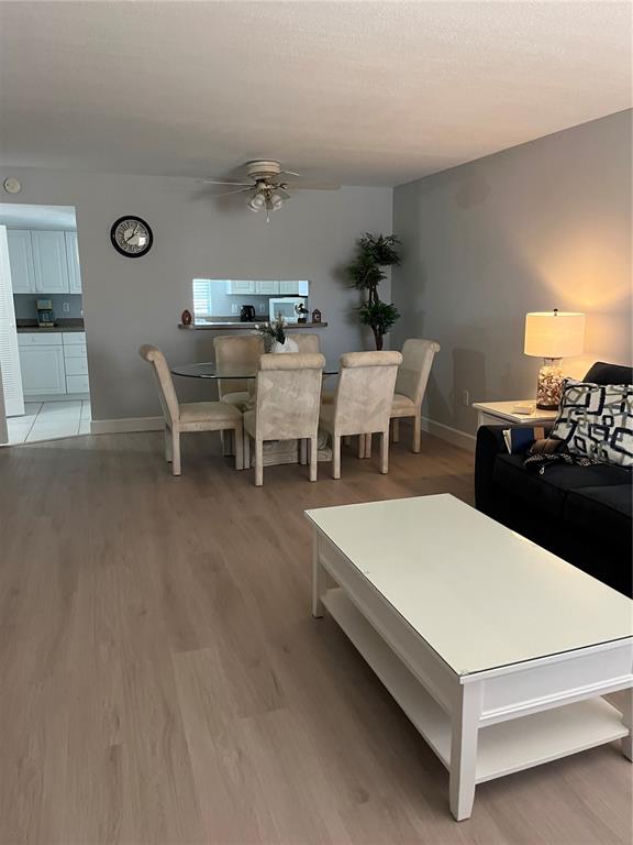 This living and dining area features light wood-look flooring, a glass table, and neutral furniture — 1531 PLACIDA ROAD UNIT 10-103, ENGLEWOOD, FL