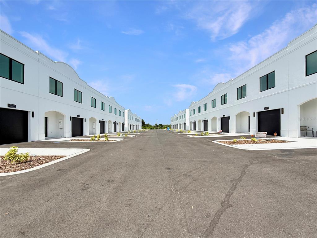 An exterior view shows two rows of identical white commercial buildings flanking a paved road — 4345 CAMBIO GARDENS COURT, TAMPA, FL