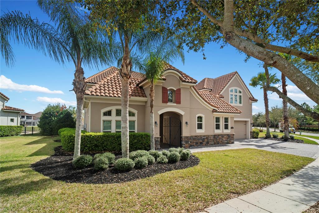 A tan stucco house with a tiled roof, stone accents, and palm trees in the yard — 7560 BLUE QUAIL LANE, ORLANDO, FL