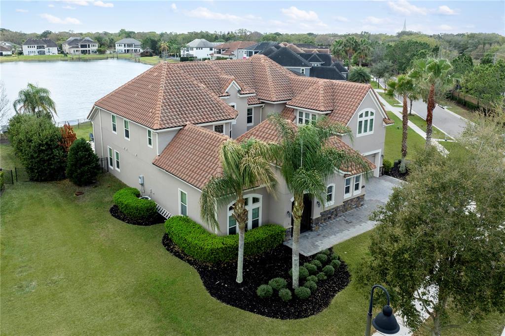 An aerial view shows a two-story house with a tiled roof near a lake — 7560 BLUE QUAIL LANE, ORLANDO, FL