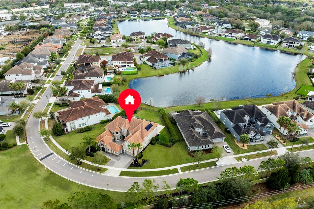 An aerial view shows a large suburban house with a tile roof near a lake — 7560 BLUE QUAIL LANE, ORLANDO, FL