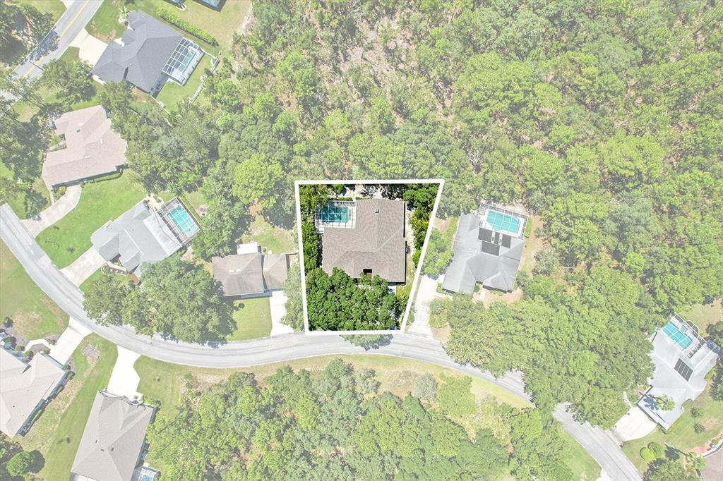 This aerial view shows a single-family home with a pool and surrounding wooded landscape — 8 SWEETGUM COURT N, HOMOSASSA, FL