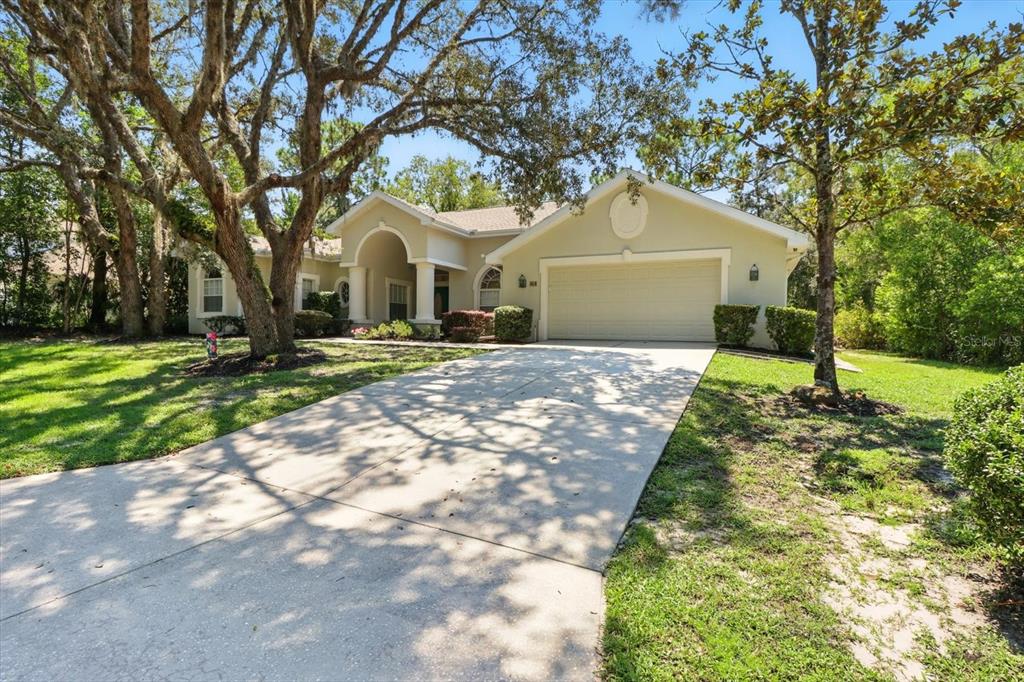 A single-story house with a beige exterior, a two-car garage, and a large front yard — 8 SWEETGUM COURT N, HOMOSASSA, FL