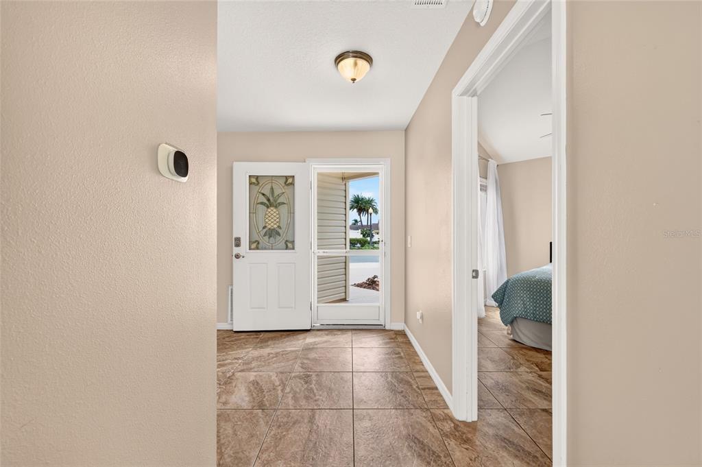 An entryway with tile flooring features a white front door with a pineapple glass insert — 1813 HORTENSIA PLACE, THE VILLAGES, FL